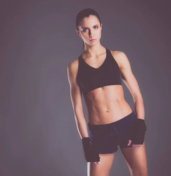 Muscular young woman posing in sportswear against black background. — Stock Photo, Image