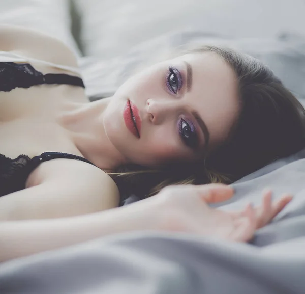 Schöne junge Frau liegt auf weißem Bett — Stockfoto