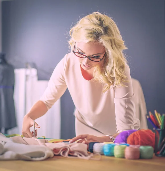 Moda tasarımcısı kadın stüdyoda tasarımları üzerinde çalışıyor.