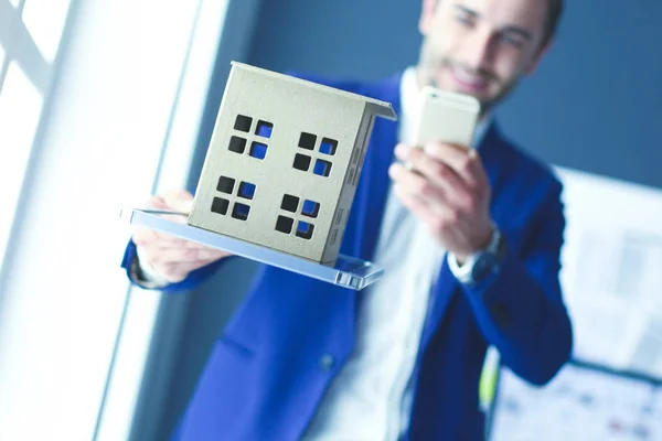 Zakenman houden huis miniatuur inzake hand status in office. — Stockfoto