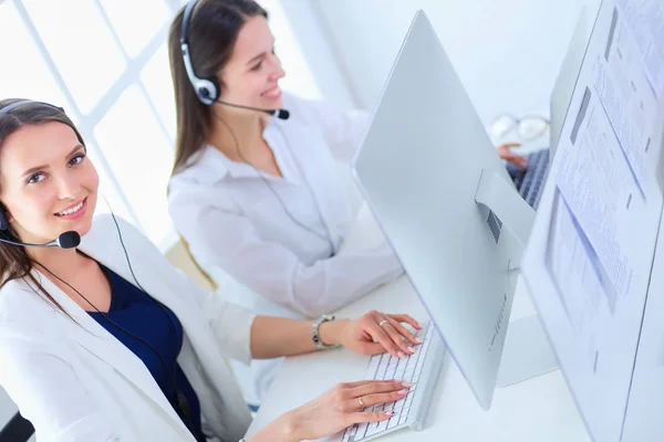 Mujer de negocios sonriente u operador de línea de ayuda con auriculares y computadora en la oficina — Foto de Stock