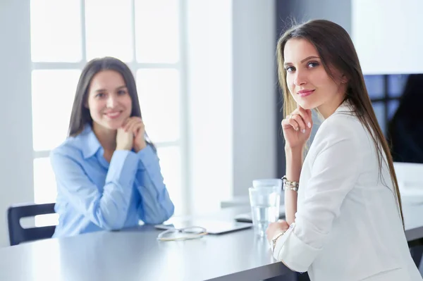 Two female colleagues in office sitting on the desk — Stock Photo, Image