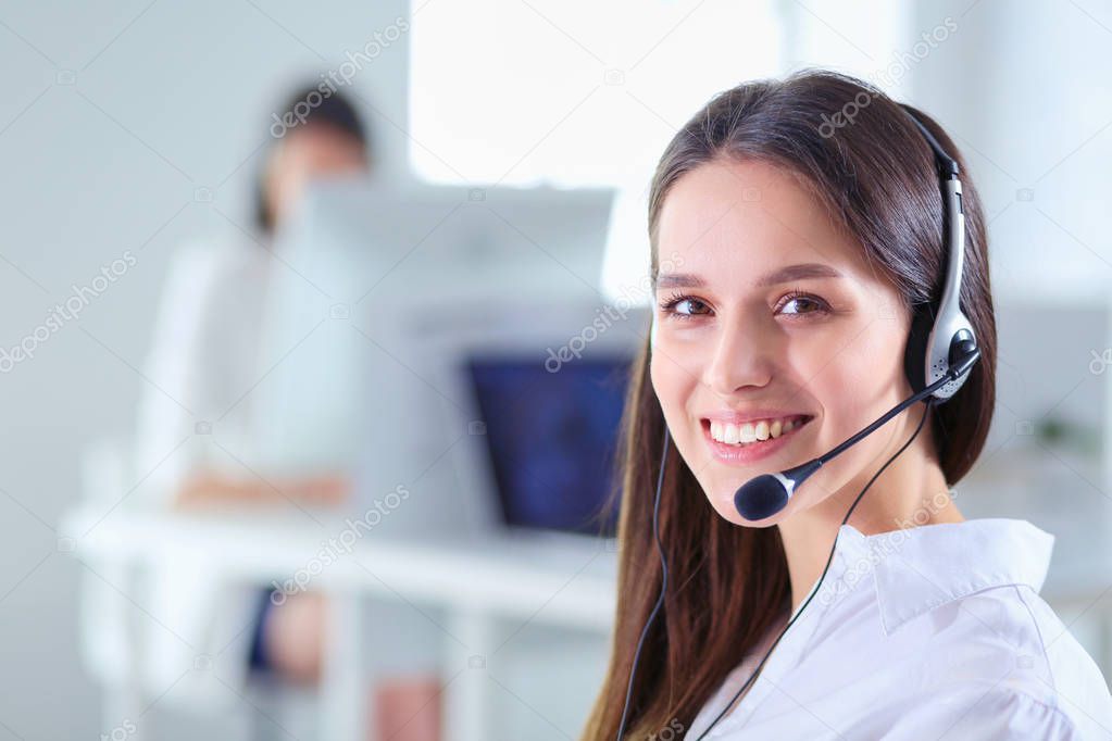 Smiling businesswoman or helpline operator with headset and computer at office