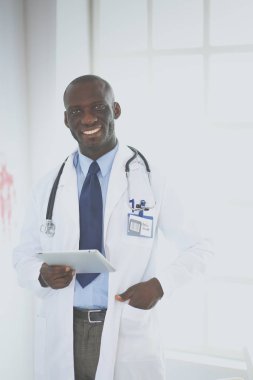 Tablet bilgisayarlı siyahi bir doktor hastanede bekliyor.