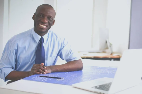 Afrikaans-Amerikaanse architect werkt met computer en blauwdrukken in kantoor — Stockfoto