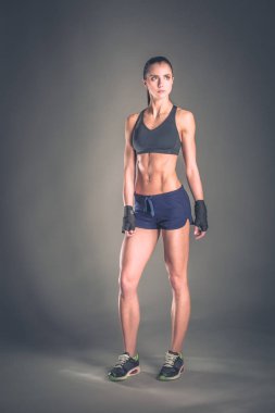 Spor giyim siyah arka plan karşı poz kas genç kadın.