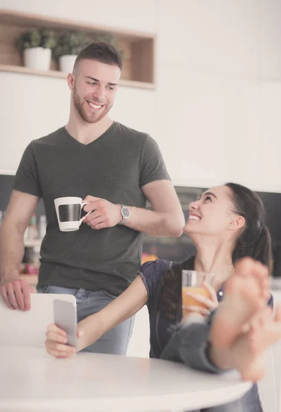 Pareja feliz usando smartphone sentado en la cocina — Foto de Stock