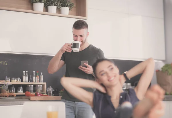 Mutlu çift mutfakta oturmuş smartphone kullanarak — Stok fotoğraf