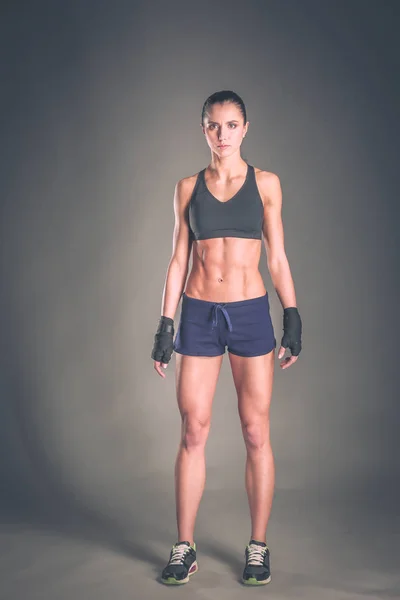 Musculosa joven posando en ropa deportiva sobre fondo negro . — Foto de Stock