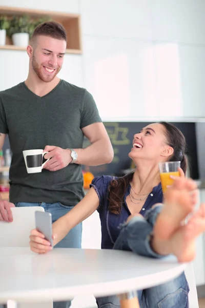 Pareja feliz usando smartphone sentado en la cocina — Foto de Stock