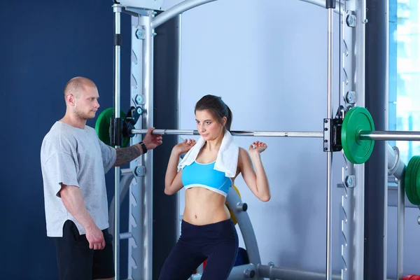 Beautiful woman at the gym exercising with her trainer. Beautiful woman. Gym