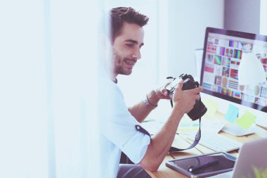 İnternette çalışırken bilgisayarın ve dizüstü bilgisayarın önünde grafik stüdyosunda oturan genç tasarımcının portresi.