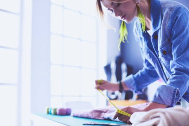 Moda tasarımcısı kadın stüdyoda tasarımları üzerinde çalışıyor.