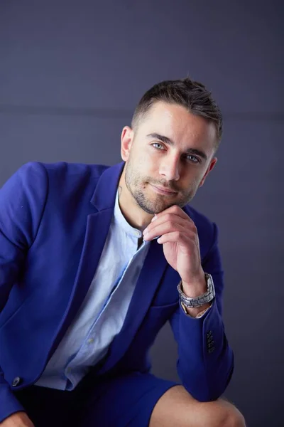 Joven empresario sentado aislado sobre fondo gris. —  Fotos de Stock