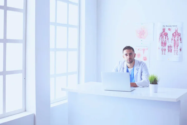 Portrait of a male doctor with laptop sitting at desk in medical office. — Stock Photo, Image