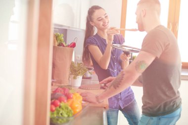 Bir çift evdeki mutfaklarında birlikte yemek pişiriyor.