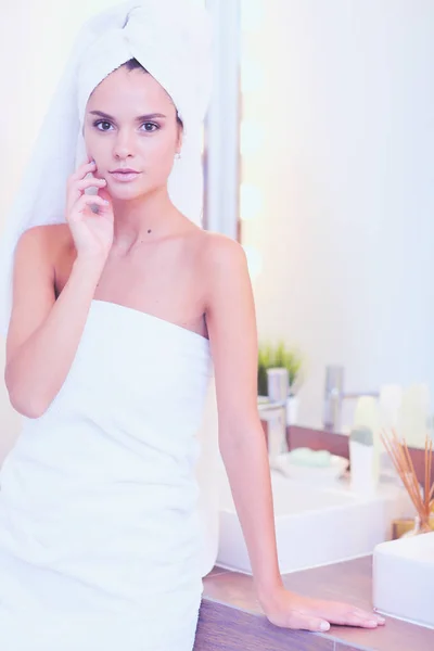 Young attractive woman standing in front of bathroom mirror — Stock Photo, Image