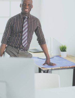 Ofiste bilgisayar ve planlarla çalışan Afrikalı Amerikalı bir mimar.