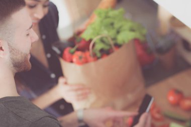 Mutlu çift Smartphone ayakta mutfakta kullanarak