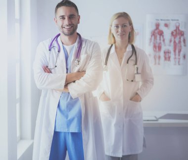 Yakışıklı doktor genç bayan doktorla konuşuyor ve ofisinde otururken notlar alıyor..