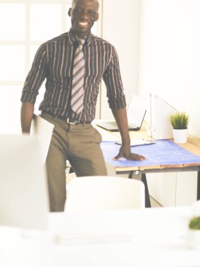 Ofiste bilgisayar ve planlarla çalışan Afrikalı Amerikalı bir mimar.