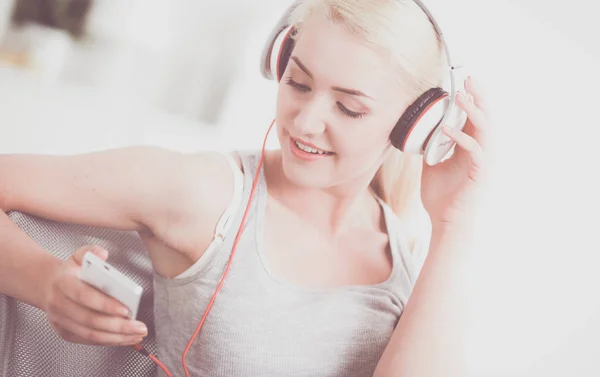 Joven hermosa mujer en casa sentada en el sofá y escuchando música —  Fotos de Stock