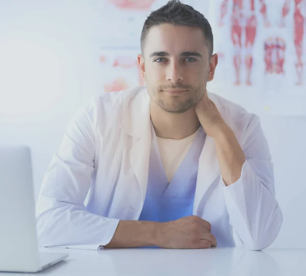 Retrato de un médico varón con portátil sentado en el escritorio en el consultorio médico. — Foto de Stock