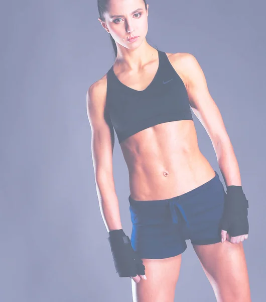 Muscular young woman posing in sportswear against black background. — Stock Photo, Image