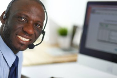 Kulaklıklı Afro-Amerikan işadamı laptopuyla çalışıyor.