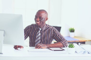Yakışıklı Afro Amerikalı işadamı Klasik takım elbiseli bir dizüstü bilgisayar kullanarak ve ofiste çalışırken gülümseyen