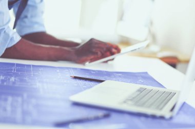 Ofiste bilgisayar ve planlarla çalışan Afrikalı Amerikalı bir mimar.