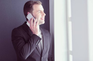 Modern ofiste cep telefonuyla konuşan yakışıklı iş adamı..
