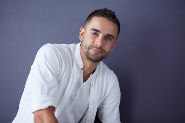 Gri arka planda yalnız oturan genç iş adamı.