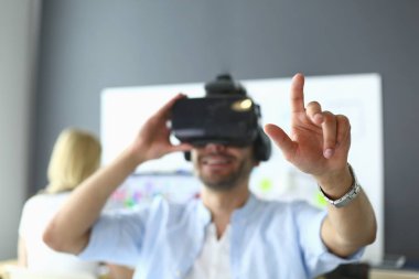 Genç erkek yazılım programcısı ofiste üç boyutlu sanal gerçeklik gözlükleriyle yeni bir uygulama test ediyor..