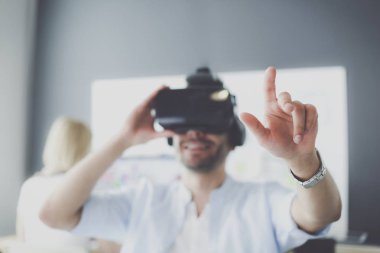 Genç erkek yazılım programcısı ofiste üç boyutlu sanal gerçeklik gözlükleriyle yeni bir uygulama test ediyor..