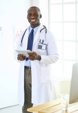 Tablet bilgisayarlı siyahi bir doktor hastanede bekliyor.