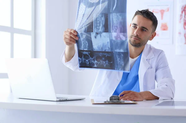 El guapo doctor está hablando con una paciente joven y tomando notas mientras está sentado en su consultorio.. — Foto de Stock