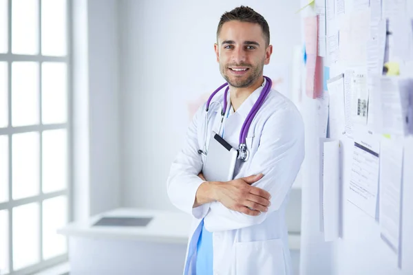 Retrato médico masculino joven y confiado de pie en el consultorio médico. — Foto de Stock