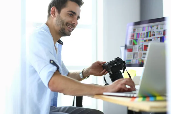 Portret młodego projektanta siedzącego w pracowni graficznej przed laptopem i komputerem podczas pracy online. — Zdjęcie stockowe