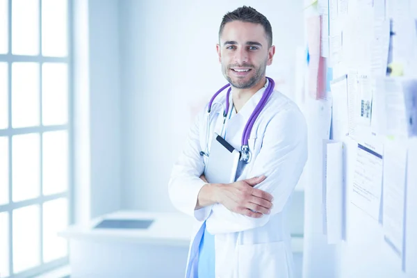 Młody i pewny siebie mężczyzna lekarz portret stojący w gabinecie medycznym. — Zdjęcie stockowe