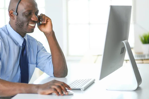 Afrikansk amerikansk affärsman på headset arbetar på sin bärbara dator — Stockfoto