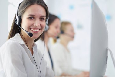 Ofisinde kulaklık ve bilgisayarla gülümseyen iş kadını ya da yardım hattı operatörü