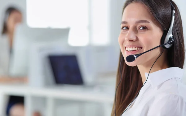 Mujer de negocios sonriente u operador de línea de ayuda con auriculares y computadora en la oficina — Foto de Stock