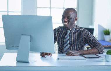 Yakışıklı Afro Amerikalı işadamı Klasik takım elbiseli bir dizüstü bilgisayar kullanarak ve ofiste çalışırken gülümseyen