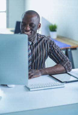 Yakışıklı Afro Amerikalı işadamı Klasik takım elbiseli bir dizüstü bilgisayar kullanarak ve ofiste çalışırken gülümseyen