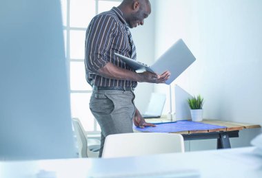 Ofiste bilgisayar ve planlarla çalışan Afrikalı Amerikalı bir mimar.