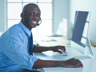 Kulaklıklı Afro-Amerikan işadamı laptopuyla çalışıyor.