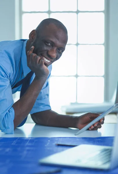 Afrikaans-Amerikaanse architect werkt met computer en blauwdrukken in kantoor — Stockfoto