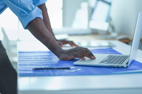 Arquiteto afro-americano trabalhando com computador e plantas no escritório — Fotografia de Stock