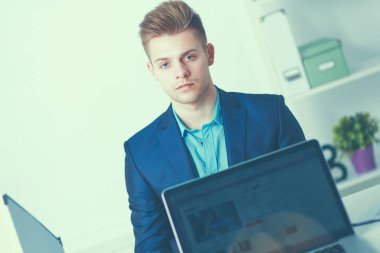 Genç işadamı ofiste çalışıyor, masada oturuyor.